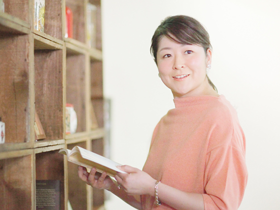 本を読みながら振り向く河合彩さん